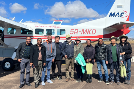 FJKM Bible translation team in front of MAF plane on airstrip in Fianarantsoa
